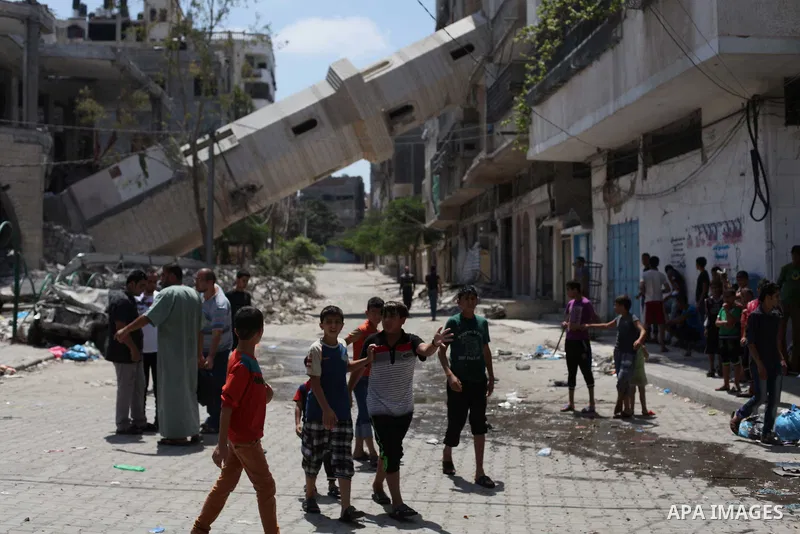 Palestinians walk past the damaged minaret of a mosque that residents said was hit in a previous Israeli air strike during the Israeli offensive, in Gaza City August 22, 2014. Since the collapse on Tuesday of a 10-day ce...