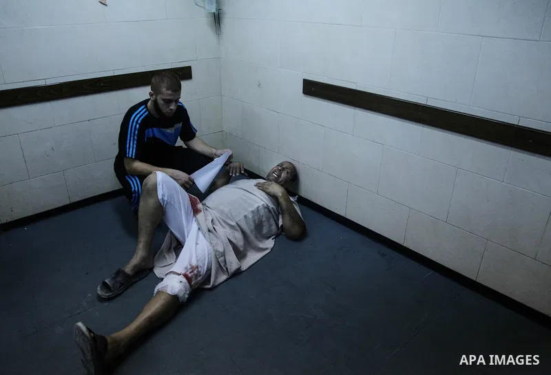 A wounded Palestinian man receives medical treatment in the corridor of the al-Shifa hospital after an Israeli air strike on Gaza City on August 22, 2014. Israeli Prime Minister Benjamin Netanyahu pledged that "Hamas wil...