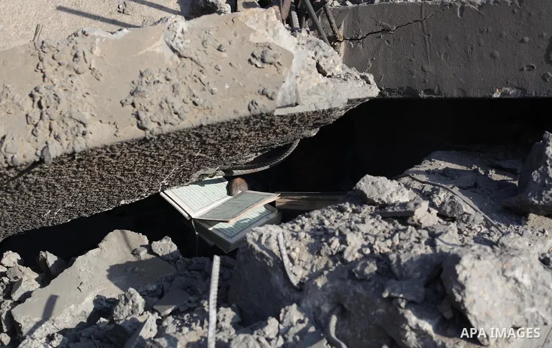A Palestinian boy carries a destroyed copies of the Koran, Islam's holy book, on August 2, 2014 after a mosque, which witnesses said was destroyed in an Israeli air strike, in Khan Younis in the southern Gaza strip Augus...