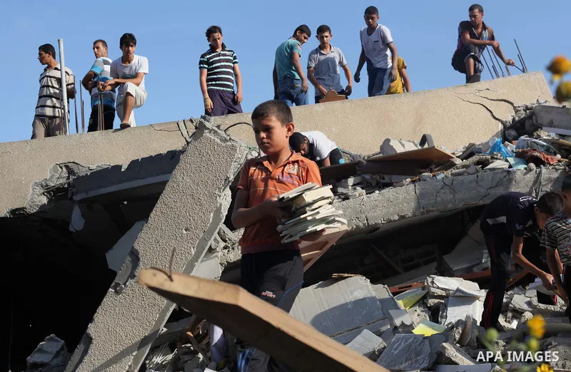 A Palestinian boy carries a destroyed copies of the Koran, Islam's holy book, on August 2, 2014 after a mosque, which witnesses said was destroyed in an Israeli air strike, in Khan Younis in the southern Gaza strip Augus...