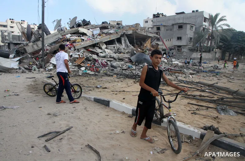 Palestinians gather around the remains of a house, which witnesses said was destroyed in an Israeli air strike, in Gaza City August 23, 2014. Hamas-led gunmen in Gaza executed 18 Palestinians accused of collaborating wit...