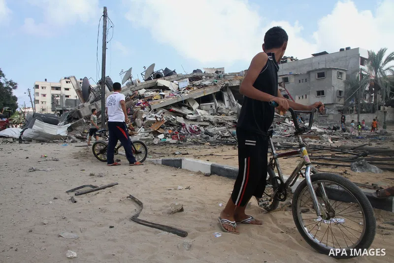 Palestinians gather around the remains of a house, which witnesses said was destroyed in an Israeli air strike, in Gaza City August 23, 2014. Hamas-led gunmen in Gaza executed 18 Palestinians accused of collaborating wit...