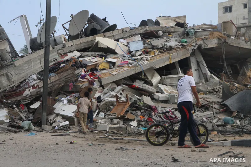 Palestinians gather around the remains of a house, which witnesses said was destroyed in an Israeli air strike, in Gaza City August 23, 2014. Hamas-led gunmen in Gaza executed 18 Palestinians accused of collaborating wit...