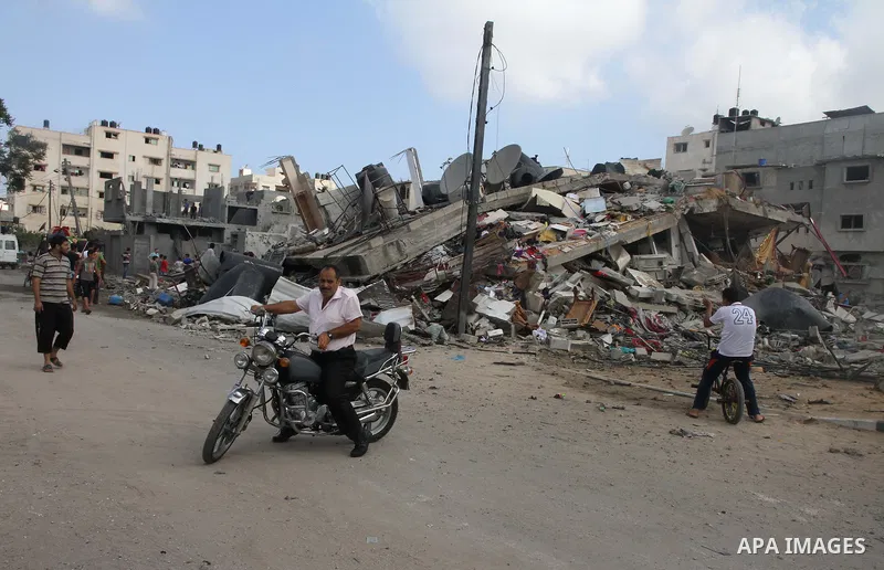 Palestinians gather around the remains of a house, which witnesses said was destroyed in an Israeli air strike, in Gaza City August 23, 2014. Hamas-led gunmen in Gaza executed 18 Palestinians accused of collaborating wit...