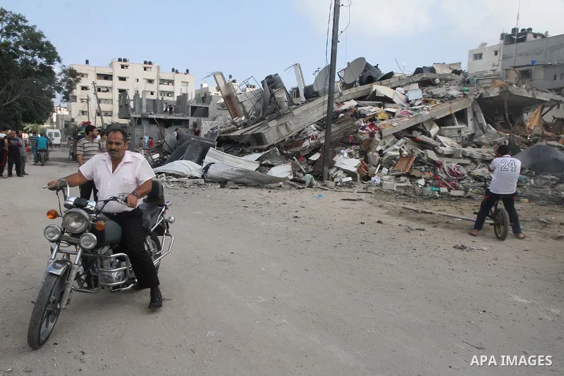 Palestinians gather around the remains of a house, which witnesses said was destroyed in an Israeli air strike, in Gaza City August 23, 2014. Hamas-led gunmen in Gaza executed 18 Palestinians accused of collaborating wit...
