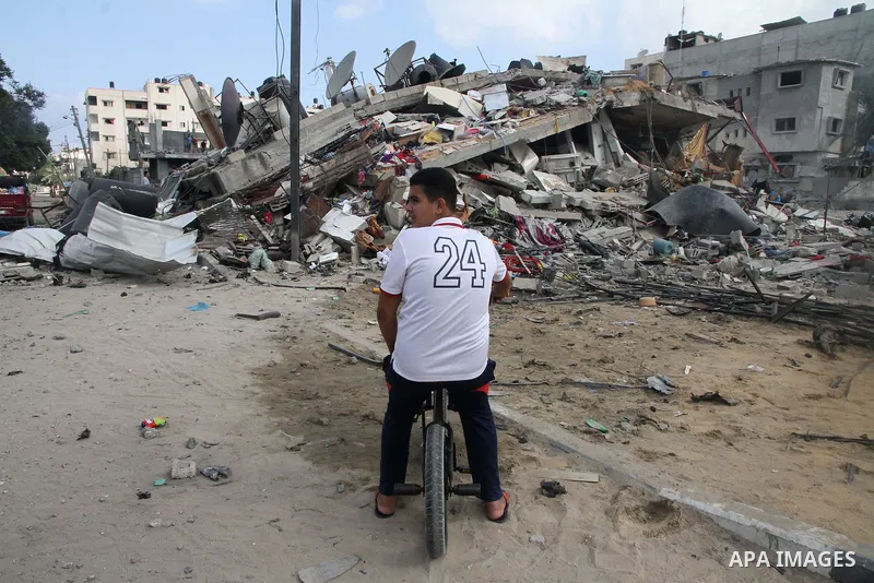 A Palestinian boy rides a bicycle past the remains a house, which witnesses said was destroyed in an Israeli air strike, in Gaza City August 23, 2014. Hamas-led gunmen in Gaza executed 18 Palestinians accused of collabor...