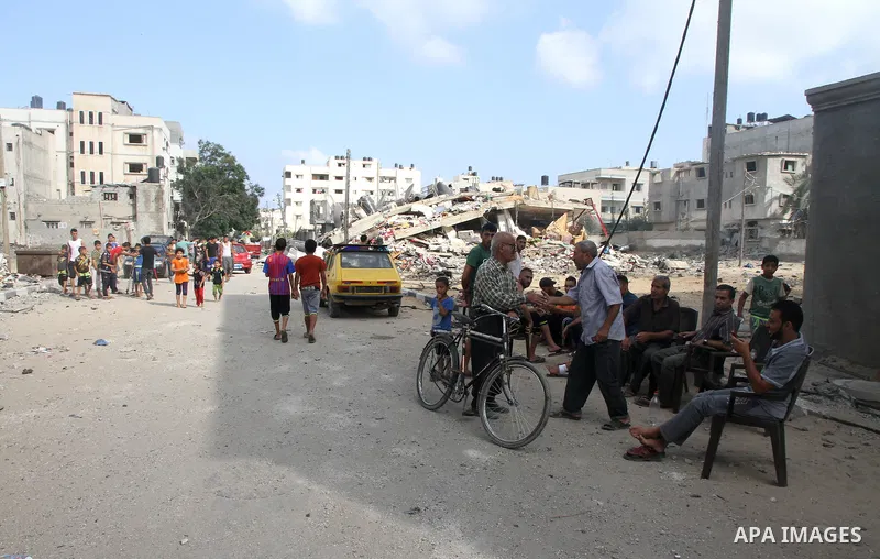 Palestinians gather around the remains of a house, which witnesses said was destroyed in an Israeli air strike, in Gaza City August 23, 2014. Hamas-led gunmen in Gaza executed 18 Palestinians accused of collaborating wit...