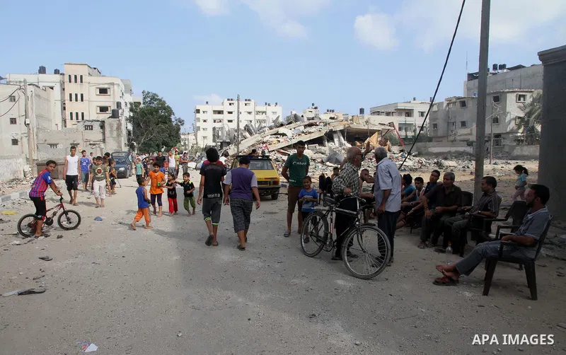 Palestinians gather around the remains of a house, which witnesses said was destroyed in an Israeli air strike, in Gaza City August 23, 2014. Hamas-led gunmen in Gaza executed 18 Palestinians accused of collaborating wit...