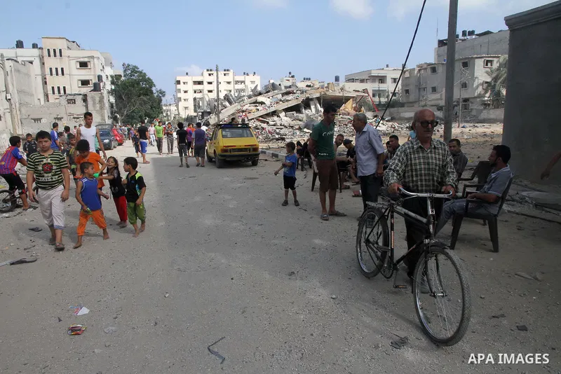 Palestinians gather around the remains of a house, which witnesses said was destroyed in an Israeli air strike, in Gaza City August 23, 2014. Hamas-led gunmen in Gaza executed 18 Palestinians accused of collaborating wit...