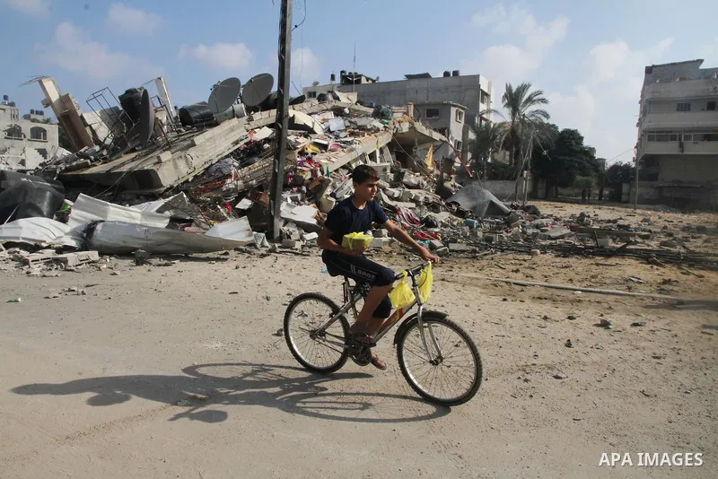 A Palestinian boy rides a bicycle past the remains a house, which witnesses said was destroyed in an Israeli air strike, in Gaza City August 23, 2014. Hamas-led gunmen in Gaza executed 18 Palestinians accused of collabor...