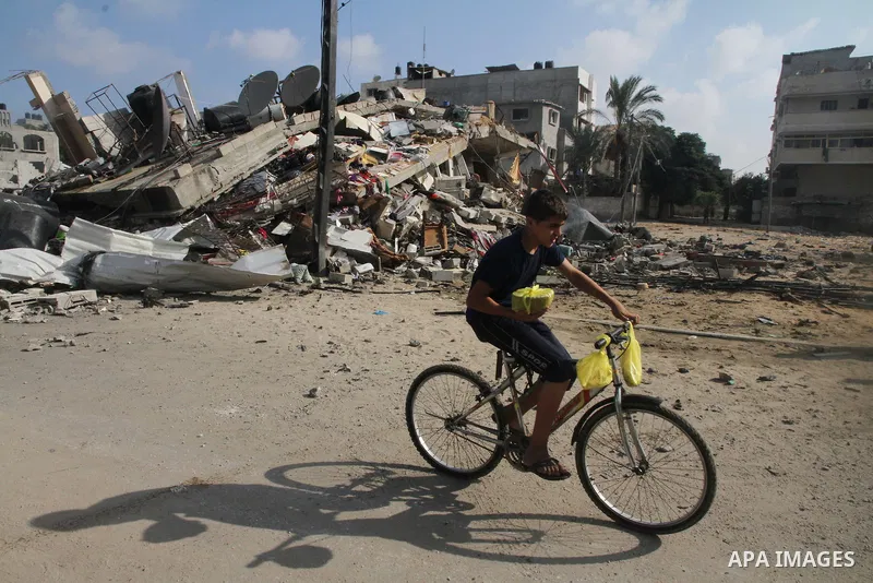 A Palestinian boy rides a bicycle past the remains a house, which witnesses said was destroyed in an Israeli air strike, in Gaza City August 23, 2014. Hamas-led gunmen in Gaza executed 18 Palestinians accused of collabor...