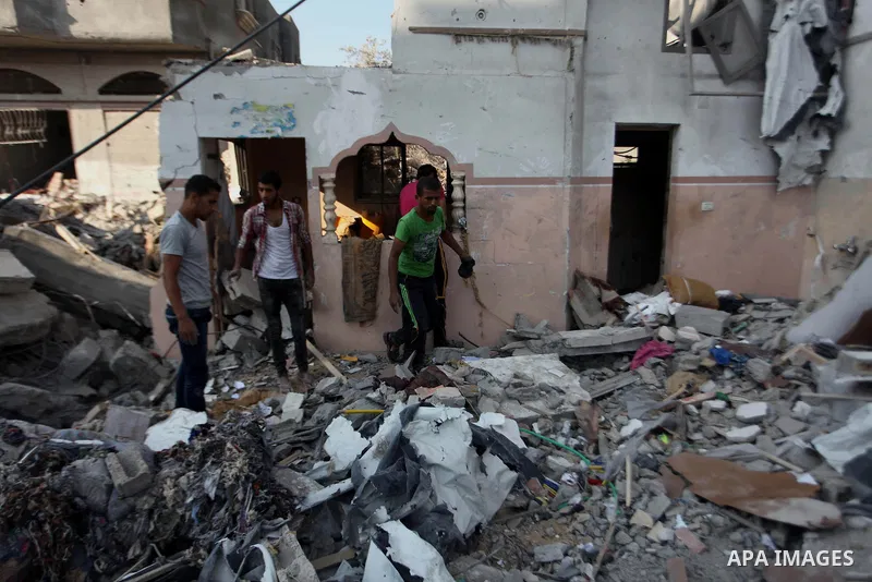 Palestinian men inspect their damaged house as the remains of another a house, which witnesses said was destroyed by an Israeli air strike, are seen in the central Gaza Strip August 23, 2014. Israeli aircraft bombed the...