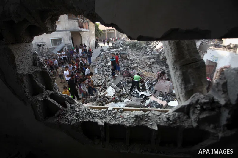 Palestinian men inspect their damaged house as the remains of another a house, which witnesses said was destroyed by an Israeli air strike, are seen in the central Gaza Strip August 23, 2014. Israeli aircraft bombed the...
