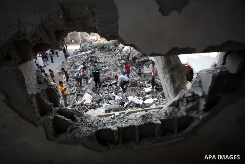 Palestinian men inspect their damaged house as the remains of another a house, which witnesses said was destroyed by an Israeli air strike, are seen in the central Gaza Strip August 23, 2014. Israeli aircraft bombed the...