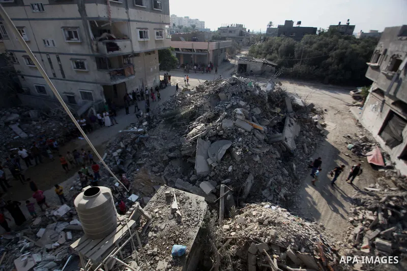 Palestinian men inspect their damaged house as the remains of another a house, which witnesses said was destroyed by an Israeli air strike, are seen in the central Gaza Strip August 23, 2014. Israeli aircraft bombed the...