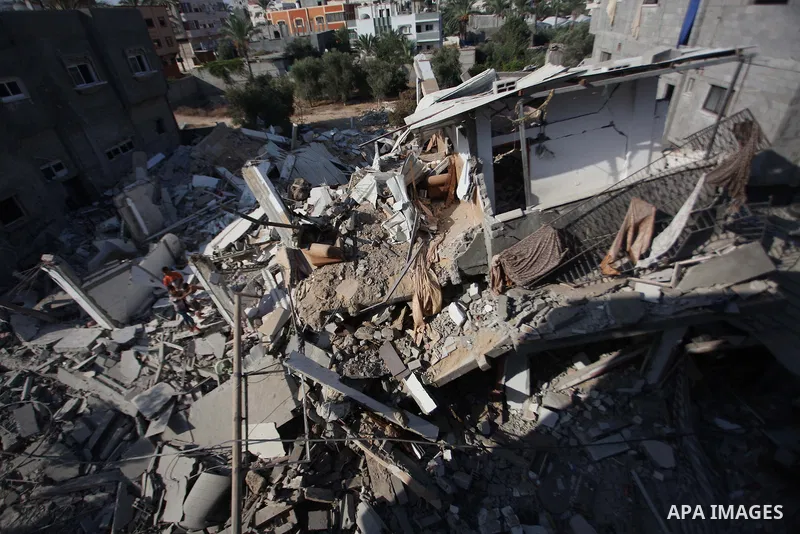 Palestinian men inspect their damaged house as the remains of another a house, which witnesses said was destroyed by an Israeli air strike, are seen in the central Gaza Strip August 23, 2014. Israeli aircraft bombed the...
