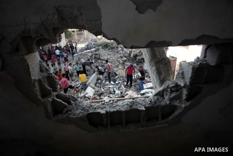 Palestinian men inspect their damaged house as the remains of another a house, which witnesses said was destroyed by an Israeli air strike, are seen in the central Gaza Strip August 23, 2014. Israeli aircraft bombed the...