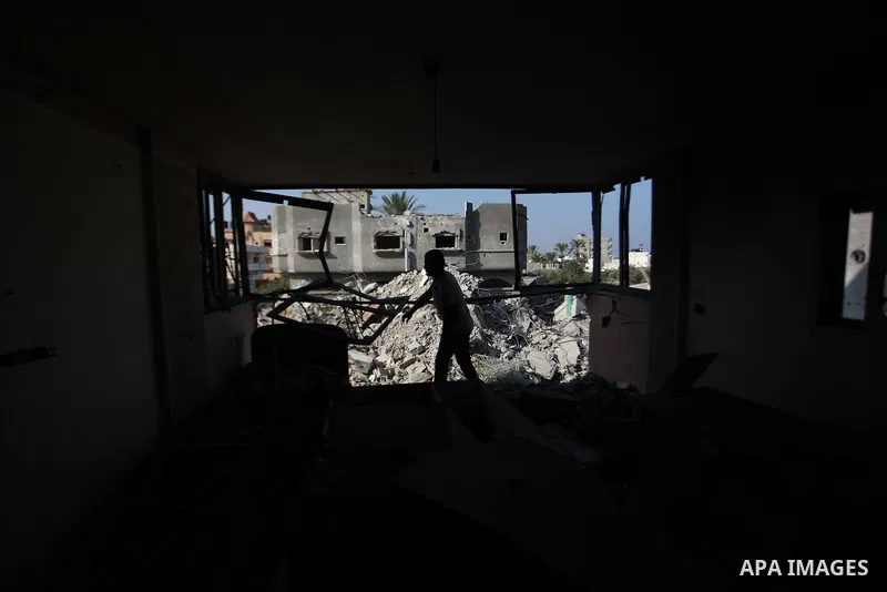 A Palestinian man inspects his damaged house as the remains of another a house, which witnesses said was destroyed by an Israeli air strike, are seen in the central Gaza Strip August 23, 2014. Israeli aircraft bombed the...