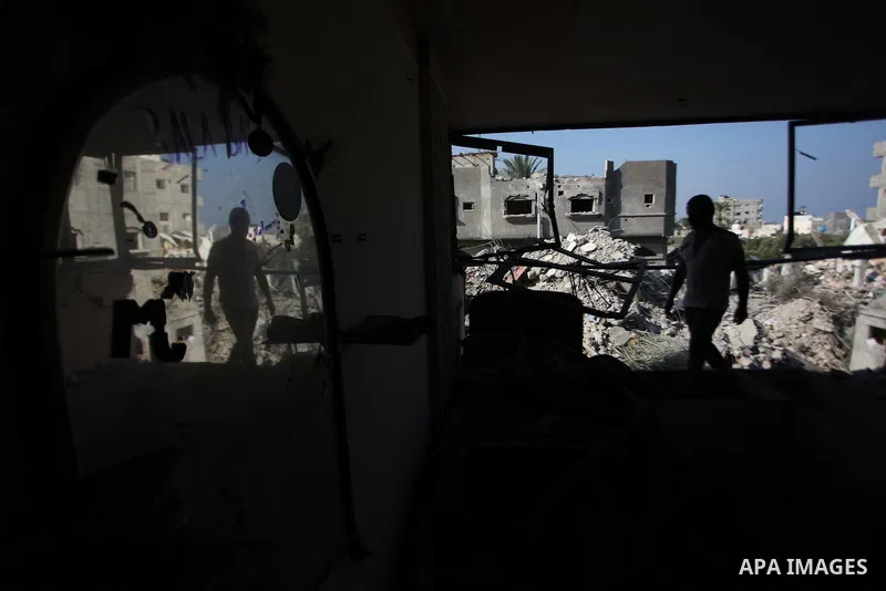 Palestinian men inspect their damaged house as the remains of another a house, which witnesses said was destroyed by an Israeli air strike, are seen in the central Gaza Strip August 23, 2014. Israeli aircraft bombed the...