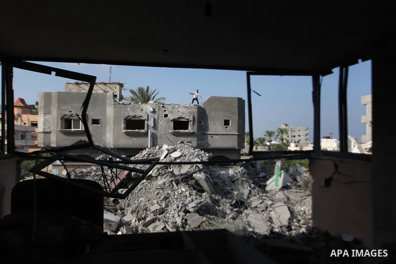 Palestinian men inspect their damaged house as the remains of another a house, which witnesses said was destroyed by an Israeli air strike, are seen in the central Gaza Strip August 23, 2014. Israeli aircraft bombed the...