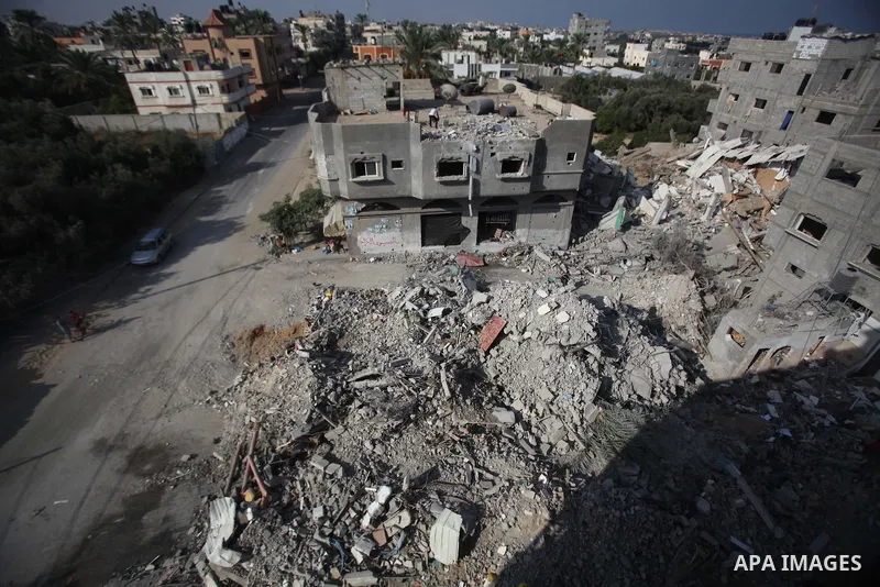 Palestinian men inspect their damaged house as the remains of another a house, which witnesses said was destroyed by an Israeli air strike, are seen in the central Gaza Strip August 23, 2014. Israeli aircraft bombed the...