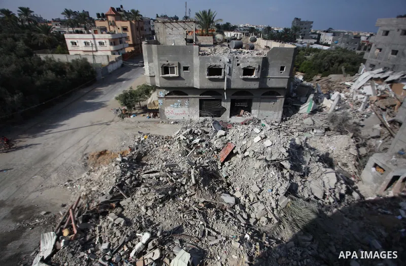 Palestinian men inspect their damaged house as the remains of another a house, which witnesses said was destroyed by an Israeli air strike, are seen in the central Gaza Strip August 23, 2014. Israeli aircraft bombed the...