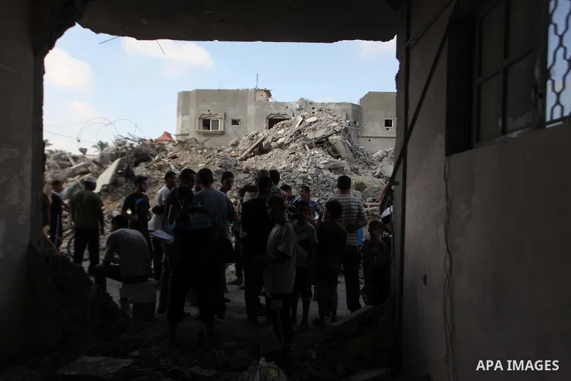 Palestinian men look at the damaged house as the remains of another a house, which witnesses said was destroyed by an Israeli air strike, are seen in the central Gaza Strip August 23, 2014. Israeli aircraft bombed the Ga...
