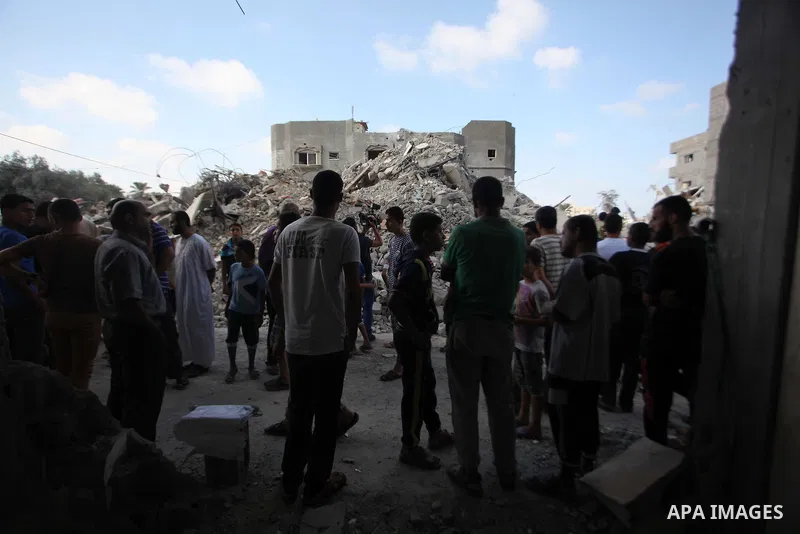 Palestinian men look at the damaged house as the remains of another a house, which witnesses said was destroyed by an Israeli air strike, are seen in the central Gaza Strip August 23, 2014. Israeli aircraft bombed the Ga...