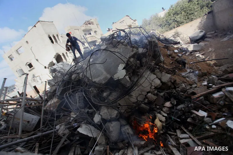 A Palestinian man inspects his damaged house as the remains of another a house, which witnesses said was destroyed by an Israeli air strike, are seen in the central Gaza Strip August 23, 2014. Israeli aircraft bombed the...