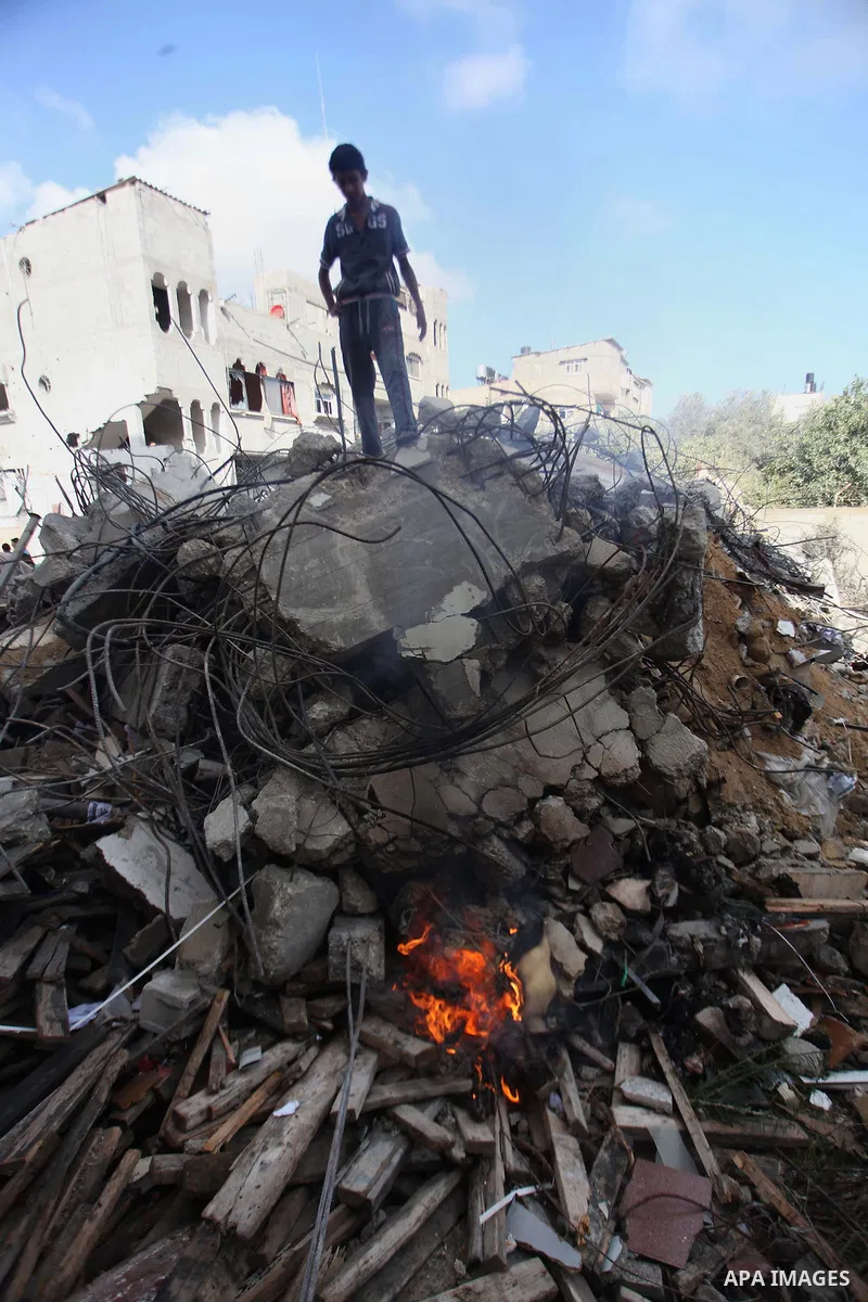 A Palestinian man inspects his damaged house as the remains of another a house, which witnesses said was destroyed by an Israeli air strike, are seen in the central Gaza Strip August 23, 2014. Israeli aircraft bombed the...