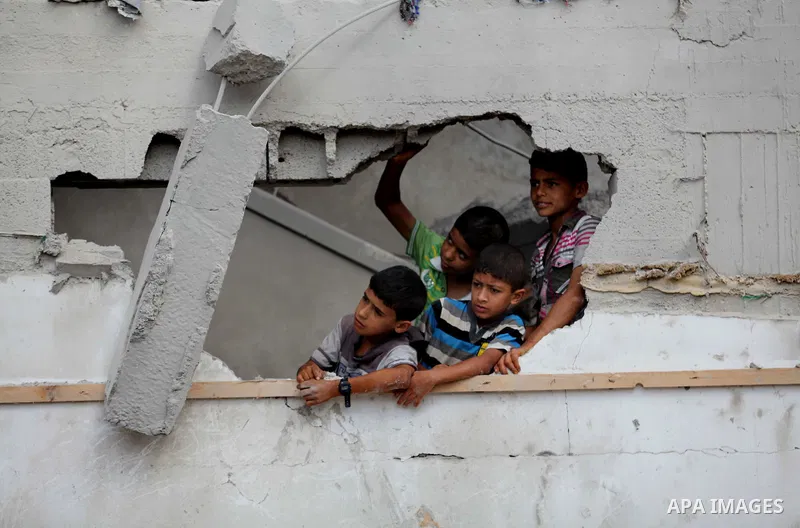 Palestinian boys look at the damaged house as the remains of another a house, which witnesses said was destroyed by an Israeli air strike, are seen in the central Gaza Strip August 23, 2014. Israeli aircraft bombed the G...