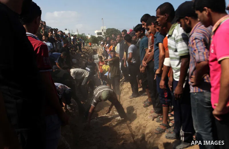 Relatives and friends bury the bodies of five Palestinians from the Abu Dahroj family, whom medics said were killed in an Israeli air strike, at cemetery in the central Gaza Strip August 23, 2014. Israeli aircraft bombed...
