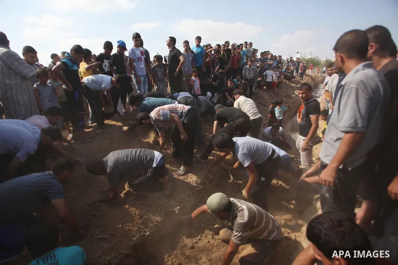 Relatives and friends bury the bodies of five Palestinians from the Abu Dahroj family, whom medics said were killed in an Israeli air strike, at cemetery in the central Gaza Strip August 23, 2014. Israeli aircraft bombed...