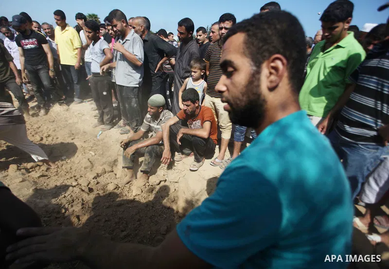 Relatives and friends bury the bodies of five Palestinians from the Abu Dahroj family, whom medics said were killed in an Israeli air strike, at cemetery in the central Gaza Strip August 23, 2014. Israeli aircraft bombed...