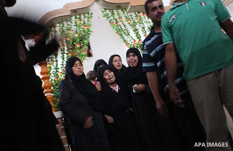 Relatives of five Palestinians from the Abu Dahroj family, whom medics said were killed in an Israeli air strike, mourn as they gather around the remains of some of their bodies during their funeral in the central Gaza S...