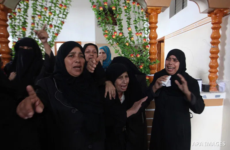Relatives of five Palestinians from the Abu Dahroj family, whom medics said were killed in an Israeli air strike, mourn as they gather around the remains of some of their bodies during their funeral in the central Gaza S...
