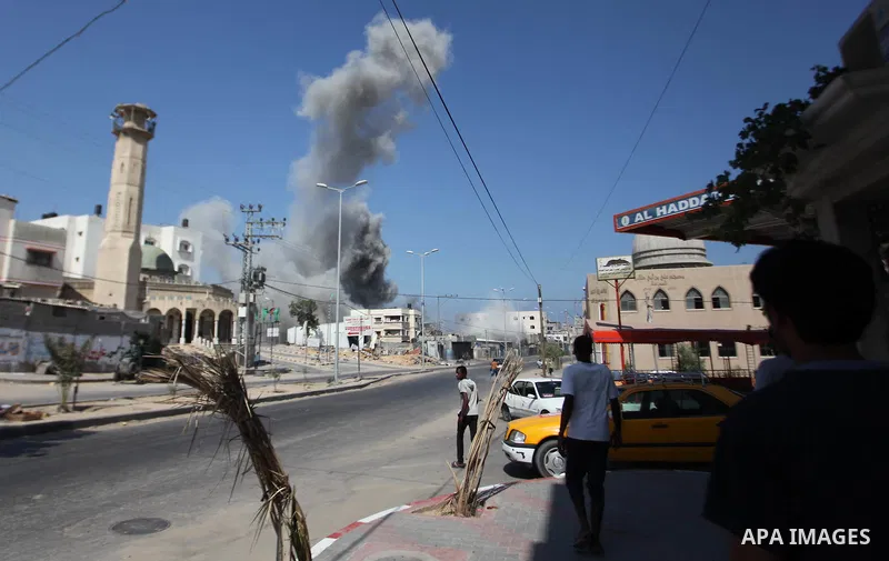 Palestinian men watch as a bomb from an Israeli air strike explodes on target in Gaza City on August 23, 2014. Israeli warplanes pounded Gaza, killing five Palestinians from the same family, two of them children, as the...