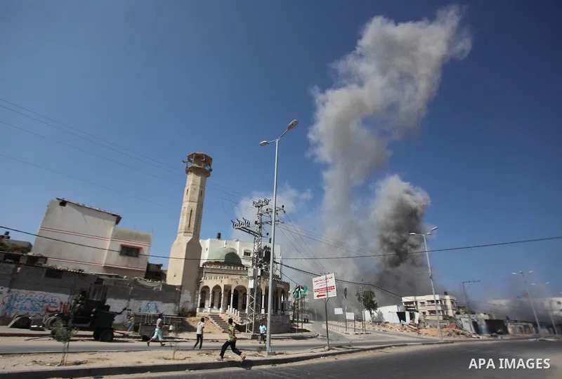 Palestinian men watch as a bomb from an Israeli air strike explodes on target in Gaza City on August 23, 2014. Israeli warplanes pounded Gaza, killing five Palestinians from the same family, two of them children, as the...