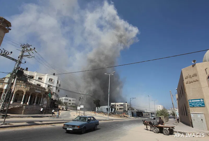 Palestinian men watch as a bomb from an Israeli air strike explodes on target in Gaza City on August 23, 2014. Israeli warplanes pounded Gaza, killing five Palestinians from the same family, two of them children, as the...