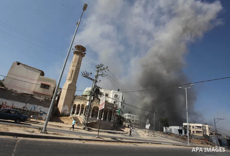 Palestinian men watch as a bomb from an Israeli air strike explodes on target in Gaza City on August 23, 2014. Israeli warplanes pounded Gaza, killing five Palestinians from the same family, two of them children, as the...