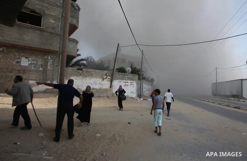 Palestinian men watch as a bomb from an Israeli air strike explodes on target in Gaza City on August 23, 2014. Israeli warplanes pounded Gaza, killing five Palestinians from the same family, two of them children, as the...