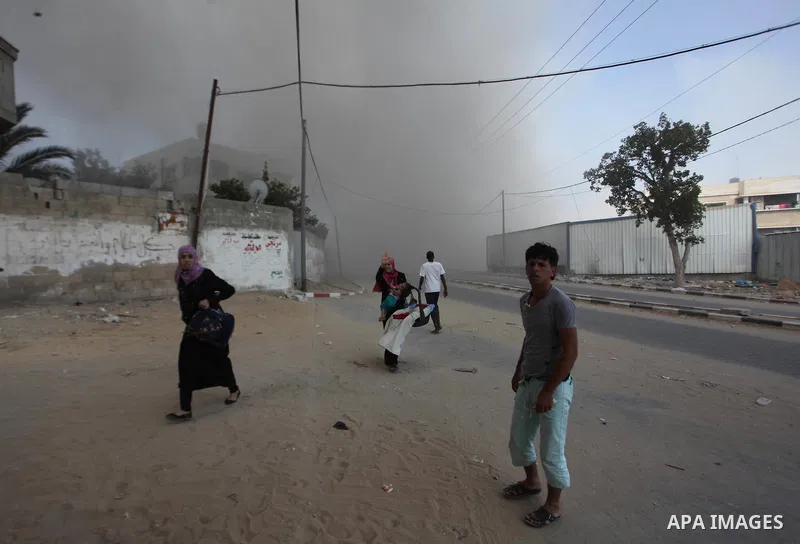 Palestinian men watch as a bomb from an Israeli air strike explodes on target in Gaza City on August 23, 2014. Israeli warplanes pounded Gaza, killing five Palestinians from the same family, two of them children, as the...