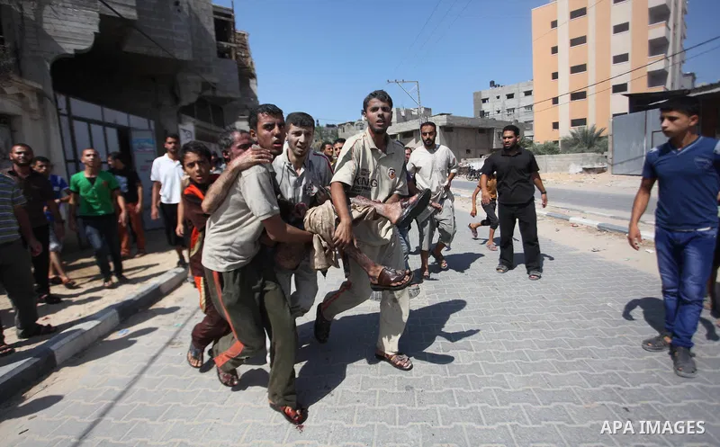 Palestinian men move a wounded man of an Israeli military strike on on target in Gaza City on August 23, 2014. Photo by Ashraf Amra