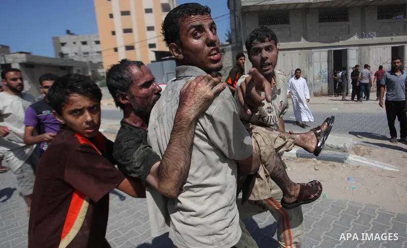 Palestinian men move a wounded man of an Israeli military strike on on target in Gaza City on August 23, 2014. Photo by Ashraf Amra