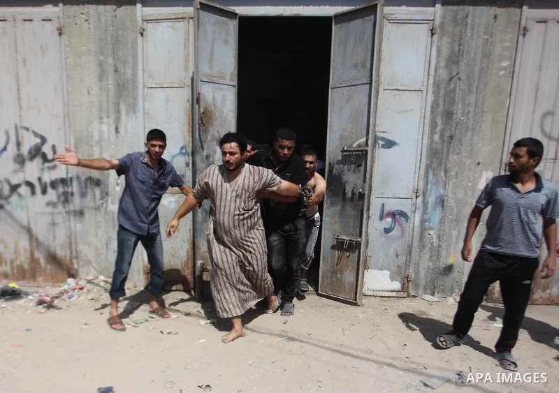 Palestinian men move a wounded man of an Israeli military strike on on target in Gaza City on August 23, 2014. Photo by Ashraf Amra