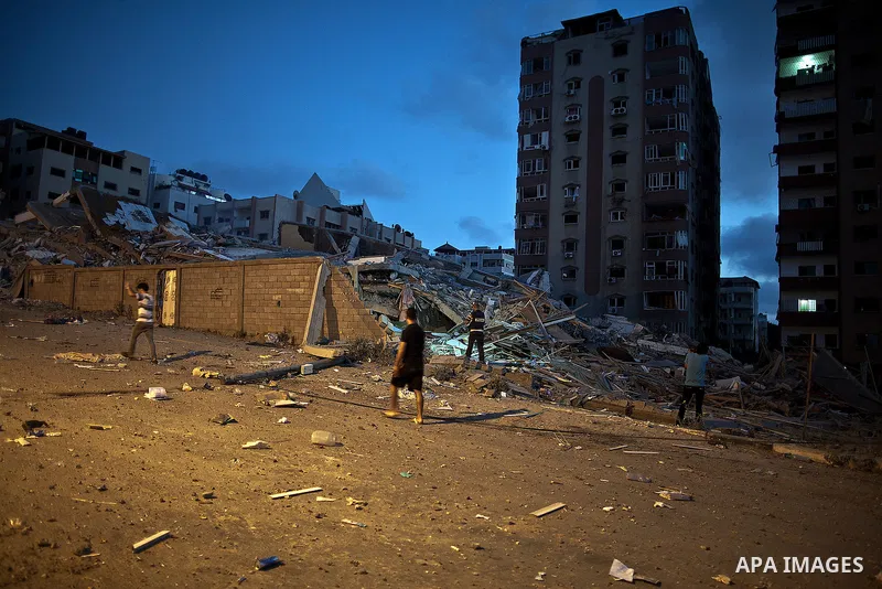 Palestinians walk next to a building that was destroyed by an Israeli air strike in Gaza City on August 23, 2014. Israel said it had carried out 55 air strikes over the Gaza Strip on August 23 and that around 45 rockets...