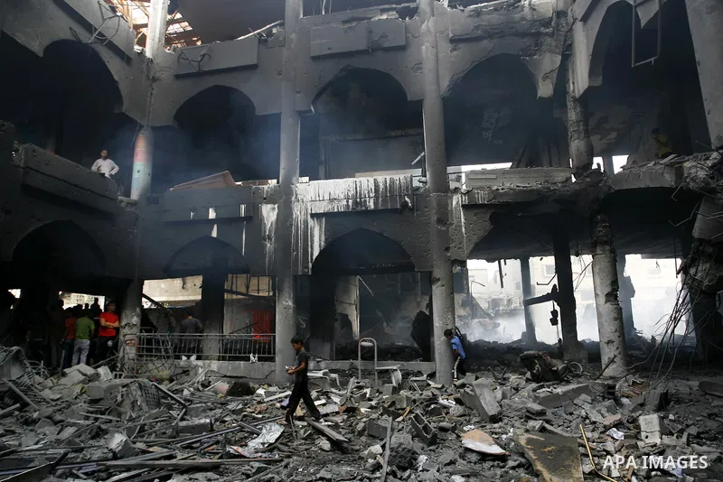Palestinians look at the remains of a commercial center, which witnesses said was hit by an Israeli air strike on Saturday, in Rafah in the southern Gaza Strip August 24, 2014. Egypt called on Israel and the Palestinians...