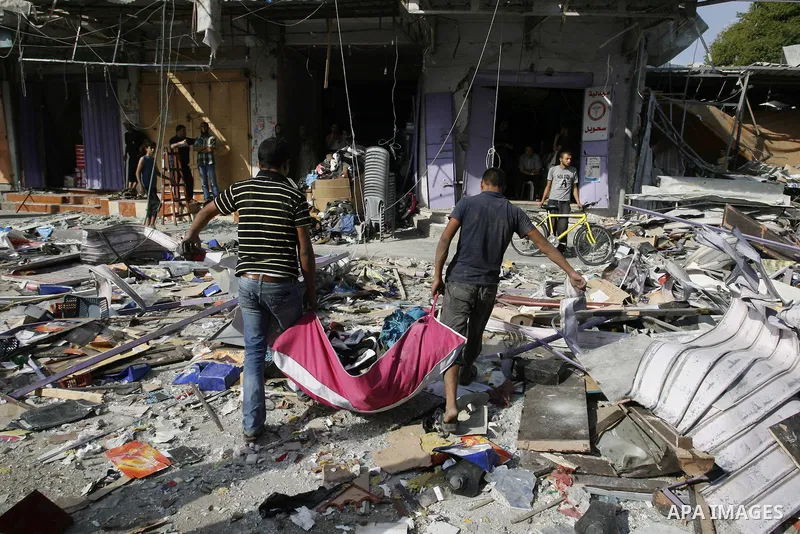 Palestinians look at the remains of a commercial center, which witnesses said was hit by an Israeli air strike on Saturday, in Rafah in the southern Gaza Strip August 24, 2014. Egypt called on Israel and the Palestinians...