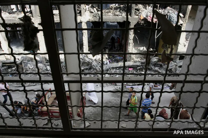Palestinians look at the remains of a commercial center, which witnesses said was hit by an Israeli air strike on Saturday, in Rafah in the southern Gaza Strip August 24, 2014. Egypt called on Israel and the Palestinians...