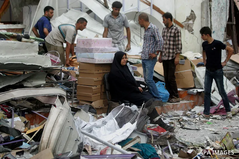 Palestinians look at the remains of a commercial center, which witnesses said was hit by an Israeli air strike on Saturday, in Rafah in the southern Gaza Strip August 24, 2014. Egypt called on Israel and the Palestinians...